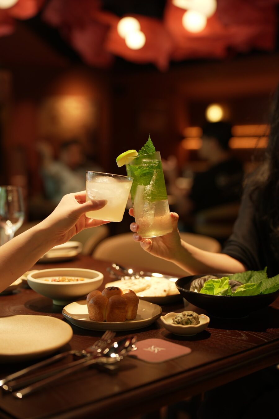 Guests toasting cocktails over the table, Liora